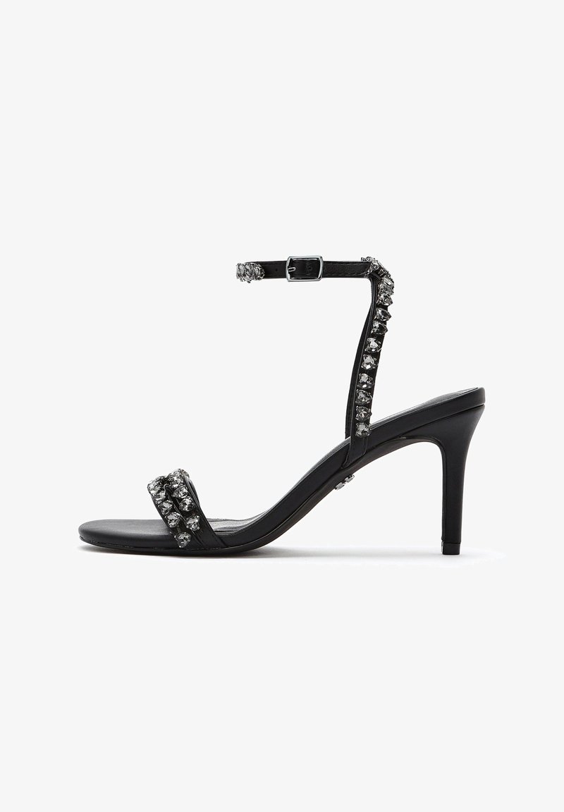 Schwarze High Heels Sandalen haben ein glänzendes Finish, zwei verzierte Riemen mit Strasssteinen und einen Knöchelriemen mit einer Metall-Schnalle.