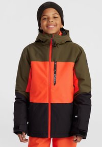 Veste d'enfant avec un haut vert olive, un milieu orange vif et un bas noir. Elle dispose d'une poche zippée et de poignets réglables.