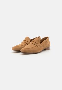 Mocasines de ante marrón con diseño slip-on, punta redonda y costuras sutiles. El tacón plano es de madera, ofreciendo un acabado texturizado.