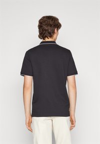 Black polo shirt with a collar, featuring white accents on the collar and sleeves. Made from a smooth fabric, with short sleeves and a relaxed fit.
