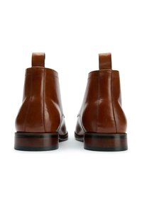Brown leather ankle boots with a smooth finish. Features a rounded shape, minimal stitching, and a wooden sole with a black accent.