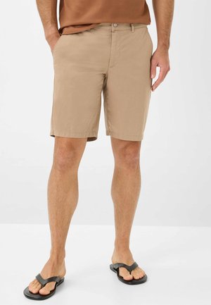 Beige shorts lavet af struktureret stof, med sidelommer, knaplukning og lige pasform, parret med sorte klipklappere.