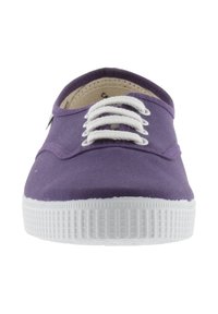 Baskets en toile violettes avec semelle en caoutchouc blanche. Présentent des lacets blancs et une pointe arrondie. Surface texturée et design minimaliste.