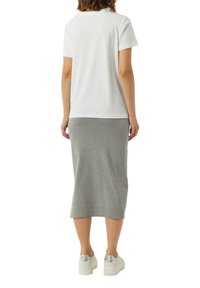 Biała koszulka z krótkim rękawem w połączeniu z szaro-skalą spódnicą o długości do kolan. Obuwie białe z srebrnymi akcentami. Prosty, casualowy design.