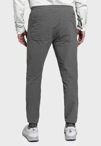 Graue Hosen mit einem dehnbaren Bund, zwei Gesäßtaschen und einem taillierten BeinDesign, kombiniert mit grau-weißen Sportschuhen.