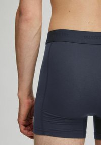 Tummansininen bokserimalli elastisella vyötärökaistalla, jossa on "SELECTED"-logo, sileä pinta ja muotoiltu malli.