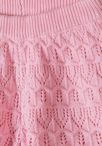 Tissu tricoté rose doux avec un bord côtelé et un motif texturé de feuilles répétées sur tout le matériau.