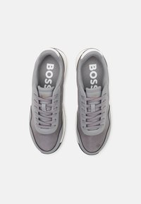 Ein Paar graue BOSS-Sneaker mit Schnürdesign und kontrastierenden weißen Sohlen, von oben auf einem weißen Hintergrund betrachtet.