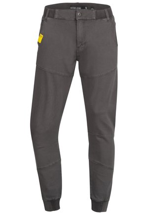 Pantalones de algodón gris con puños elásticos, que presentan un parche de logo lateral y detalles de costura en contraste. Diseñados con un corte ajustado.