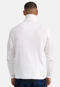 Weißer Strickpullover mit hohem Kragen, ausgestattet mit strukturierten Zopfstrickärmeln und einem gerippten Saum. Glatter Körper und strukturiertes Design.