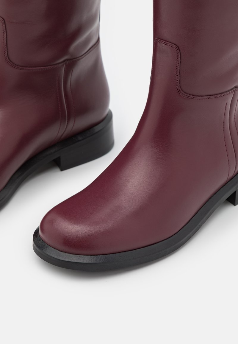 Bordeauxfarbene Lederstiefeletten mit einer runden Zehenform, glatter Textur und einem niedrigen, schwarzen Blockabsatz. Verfügt über subtile Nähte und keine sichtbaren Beschläge.