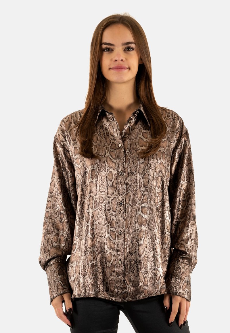 Camisa de manga larga de estampado de serpiente marrón con cuello clásico, cierre de botones en la parte delantera y una textura suave y brillante. Combinada con pantalones negros.