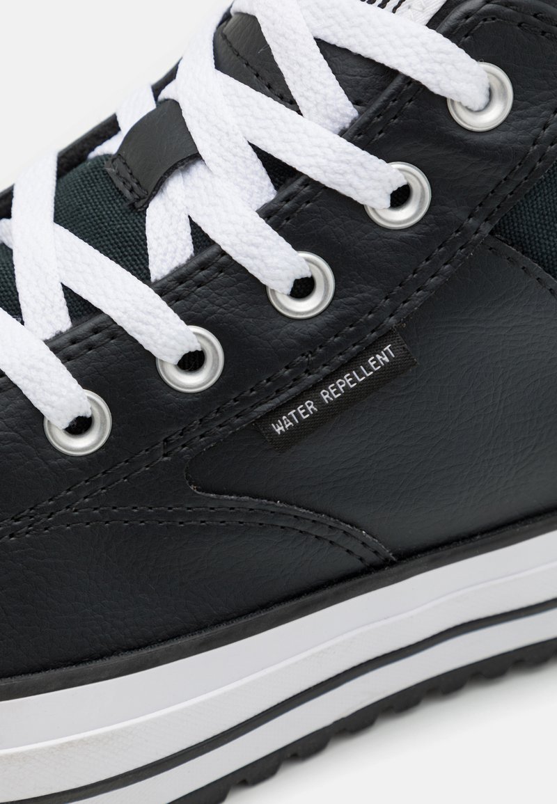 Sort vandafvisende sneakers med hvide snørebånd, metaløjer og en tekstureret overflade. Har en hvid og sort stribet sål.