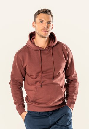 Maroon hoodie with a kangaroo pocket, drawstrings, and ribbed cuffs. Soft fabric with a smooth texture. Worn with navy pants.