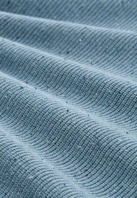 Strukturierter Baumwollstoff in sanftem Blau, mit einem gerippten Muster und subtilen Sprenkeln, die in horizontalen Falten angeordnet sind.