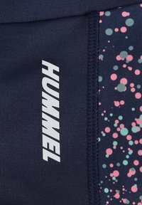 Mornarske športne kratke hlače z belim logotipom "HUMMEL". Imajo barvit pikčast vzorec v roza in zeleni barvi na črnem panelu. Gladek tekstura tkanine.
