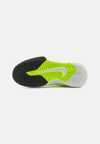 Sportssko sål med et sort og limegrønt gummidesign, der har en struktureret overflade og en hvid accent, som fremhæver skridsikre mønstre.