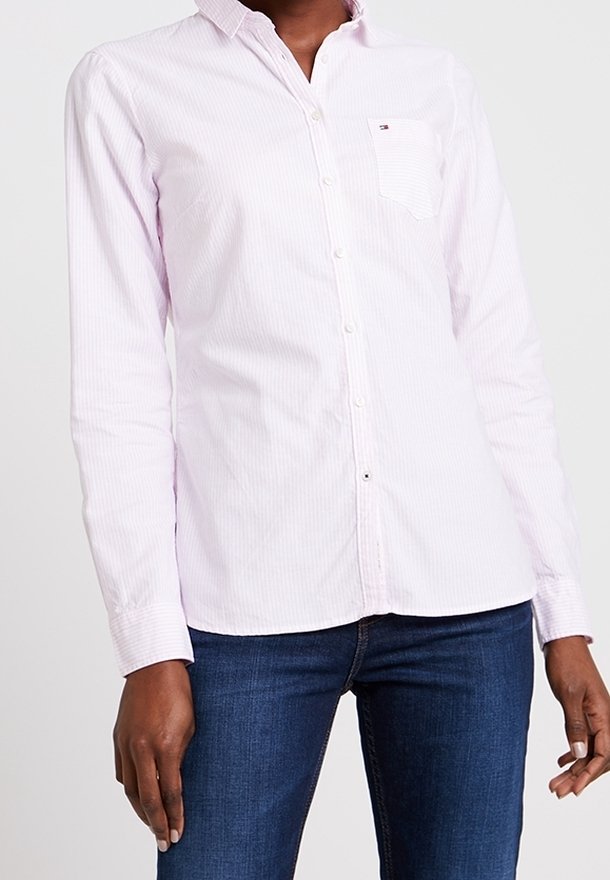 Camicia button-up rosa chiaro con strisce bianche, maniche lunghe e una singola tasca sul petto. Realizzata in una leggera mischia di cotone.