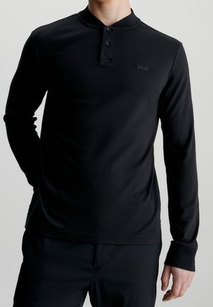 Schwarzes langärmeliges Henley-Shirt mit Kragen und dreiknöpfiger Leiste. Hergestellt aus glattem, flexiblem Stoff, mit einem dezenten Markenlogo.