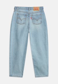 Ανοιχτό μπλε τζιν με πίσω τσέπες, καφέ δερμάτινο λογότυπο Levi's στη ζώνη, και κόκκινη υφασμάτινη ετικέτα Levi's στην δεξιά τσέπη.