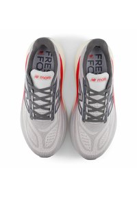New Balance running shoes in gray and red; breathable mesh upper with patterned texture, lace-up design, cushioned midsole, and rubber outsole.