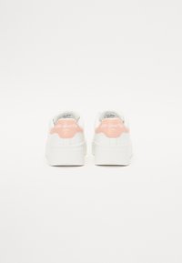 Sneaker bianche con suola spessa, dotate di un accento in pelle rosa sul tallone con la scritta "Aldo Sport Club" in rilievo. Texture liscia.