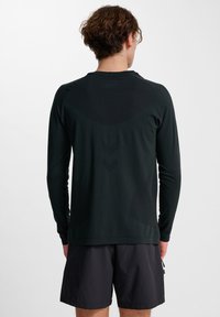 Zwart sportshirt met lange mouwen, gemaakt van gladde stof, met een aansluitend ontwerp en subtiele textuuraccenten op de achterkant.