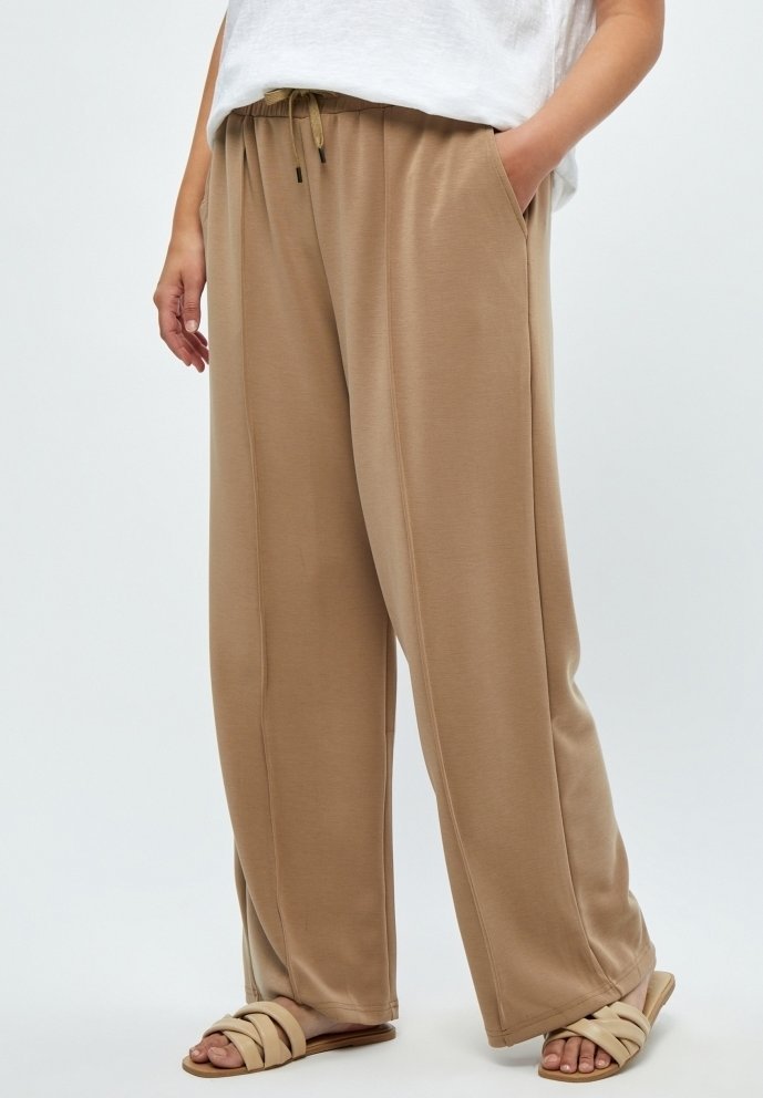 Beige wijde broek van zachte stof, met een elastische tailleband met trekkoord, zijzakken en een gladde textuur.
