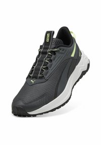 Chaussure de sport noire avec un dessus en maille texturée, accents verts et une semelle blanche épaisse. Présente un col rembourré et des lacets contrastants.