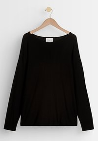 Pull noir à manches longues avec un large décolleté, fabriqué en tissu doux. Présente des épaules tombantes et des poignets côtel és. Suspendu à un cintre en bois.