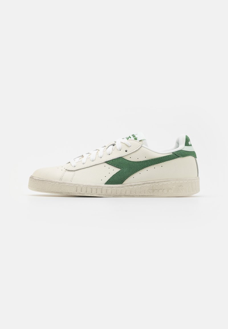 Hvite lær sneakers med grønne semskede detaljer, rund tå, snøring, teksturert gummisåle og logo på tungen og hælen.