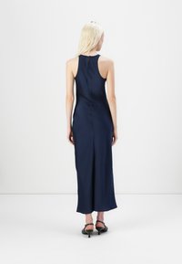 Mørkeblå satin kjole med høy hals og slisse bak. Har detalj med spalte i ryggen og når til midten av leggen. Ballerinaer brukes.