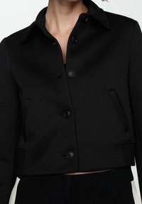 Czarna krótka kurtka z mieszanki wełny, z kołnierzem, przednimi guzikami i bocznymi kieszeniami, o gładkiej teksturze i dopasowanym kroju.