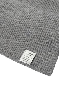 Grå ribbet strikket stoff med en hvit sydd etikett som sier "Pepe Jeans London, et denimmerke som er basert i London siden 1973."