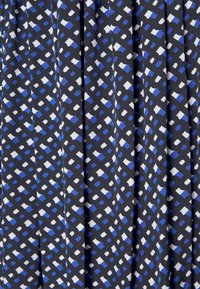 Jupe en tissu plissé avec un motif géométrique de couleurs bleu, blanc et noir. Le matériau a une texture lisse et tombe gracieusement.