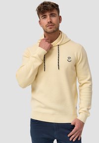 Sudadera de algodón amarilla con bolsillo frontal, capucha con cordones, puños y dobladillo de canalé, que presenta un logo bordado negro en el pecho.