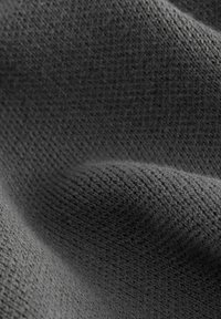Tissu gris foncé avec un motif tricoté texturé, présentant des fibres douces et légèrement surélevées ainsi qu'une surface lisse avec des plis doux.