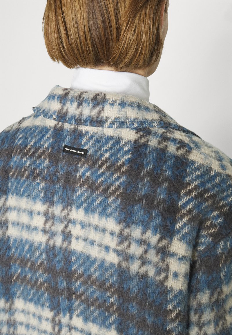 Chaqueta de mezcla de lana a cuadros en azul, blanco y gris. Presenta una etiqueta con el nombre "PEPE JEAN LONDON" en la parte posterior, con una superficie texturizada.