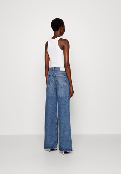 Lys blå vide jeans laget av denim, med middels livhøyde, baklommer, og råkant, parret med en hvit tanktop.
