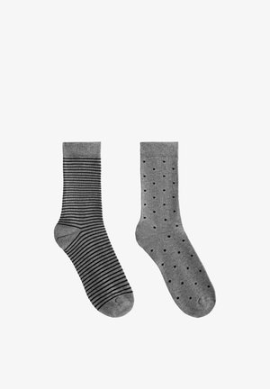 Szare skarpetki: na lewej czarne paski, na prawej czarne kropki. Obie mają ściągacze i gładką fakturę tkaniny.