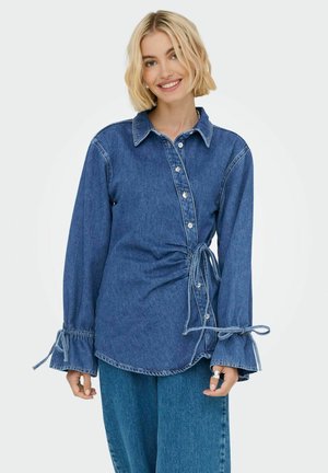 Denim-Hemd mit langen Ärmeln, durchgehender Knopfleiste und mit Schleifen gebundenen Manschetten. Verfügt über eine geraffte Seitendetail. Dunkelblau mit einer leicht strukturierten Oberfläche.