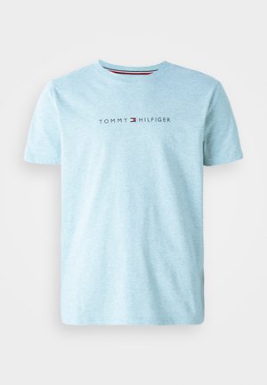 Jasnoniebieska bawełniana koszulka z okrągłym dekoltem, z logo "TOMMY HILFIGER" w czarnym tekście na wysokości klatki piersiowej, z czerwonymi i białymi akcentami.