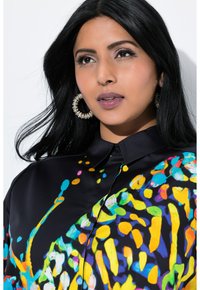 Bunte, gemusterte Seidenbluse mit schwarzem Grund und lebhaften Farbspritzern in Blau, Gelb und Pink; enthält einen Kragen und Knöpfe.