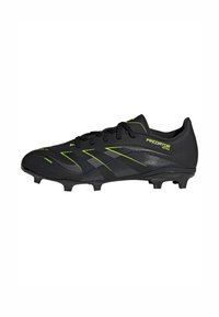 Czarne korki piłkarskie Adidas Predator z żółtymi akcentami i formowanymi kolcami na białym tle.
