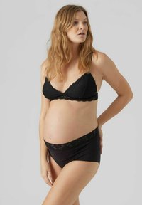 Črna bralette s čipkastimi robovi in črne materinske hlačke, ki prikazujejo gladko teksturo in podporen fit za nosečniški silhuet.