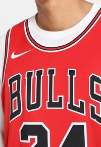 Červený basketbalový dres vyrobený z síťoviny, s černým nápisem "BULLS" a číslem "24", bílými akcenty a žebrovaným výstřihem.