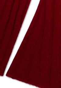 Dieprood ribgebreide stof met een zachte textuur, voorzien van verticale lijnen en een iets rafelige rand, die het warme ontwerp benadrukt.