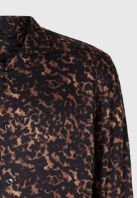 Camicia con stampa leopardata in nero e marrone, maniche lunghe, design con colletto, realizzata in un tessuto morbido, con chiusura a bottoni.