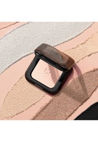 Compact poeder make-up met het merk "KIKO", omringd door gestructureerde stalen van beige, bruin, zwart en glinsterende pigmenten op een roze achtergrond.