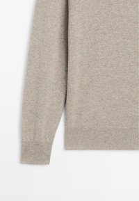 Maglione beige a maglia con maniche lunghe, caratterizzato da polsini e orlo a costine, realizzato in un morbido tessuto testurizzato con un delicato motivo melange.